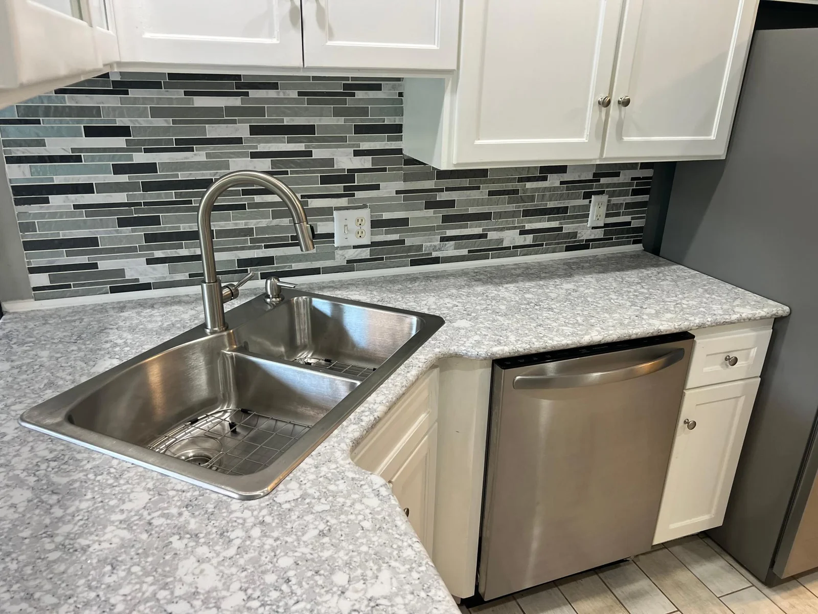 THE SINK, DISHWASHER, WITH FRIDGE BEYOND.