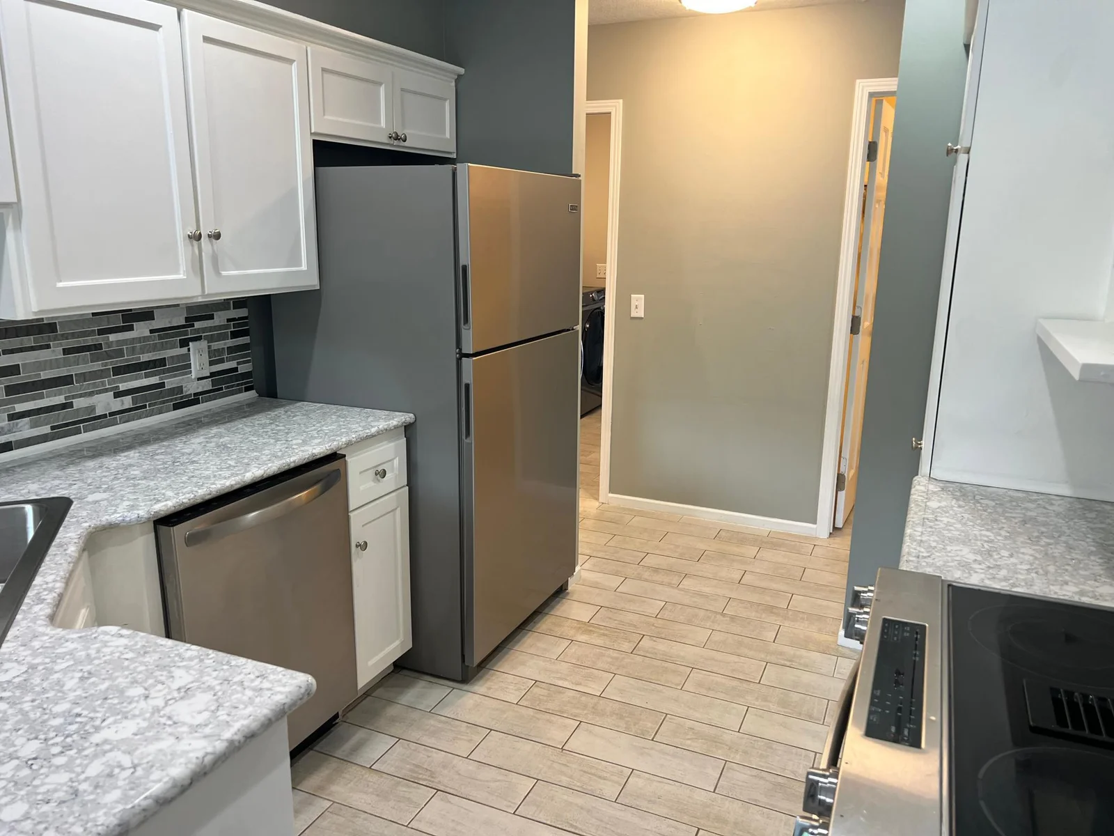 THIS VIEW SHOWS A GLIMPSE OF THE LAUNDRY ROOM AT THE BACK WALL, WITH THE WALK-IN PANTRY AT THE RIGHT.