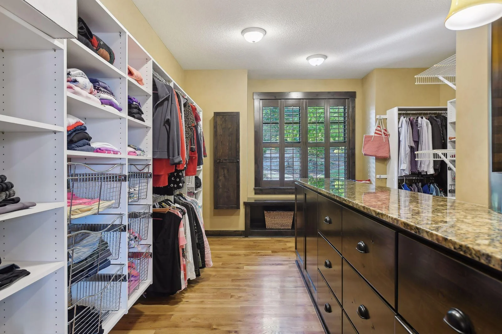 The primary closet is spacious with built-in dresser with granite counter, custom organizer system, built-in window bench and wall mounted ironing board.