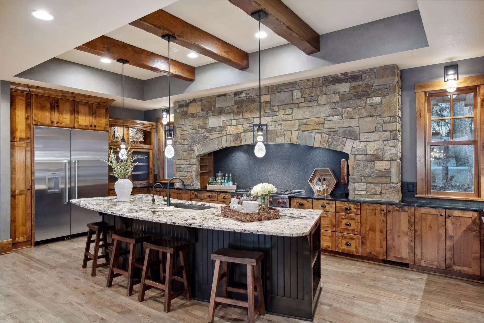 The kitchen is at the center of this home and features a 13' granite topped island, knotty alder cabinetry with soft-close doors and drawers, and cabinets with pull-out shelving and glass cabinetry doors with interior accent lighting.