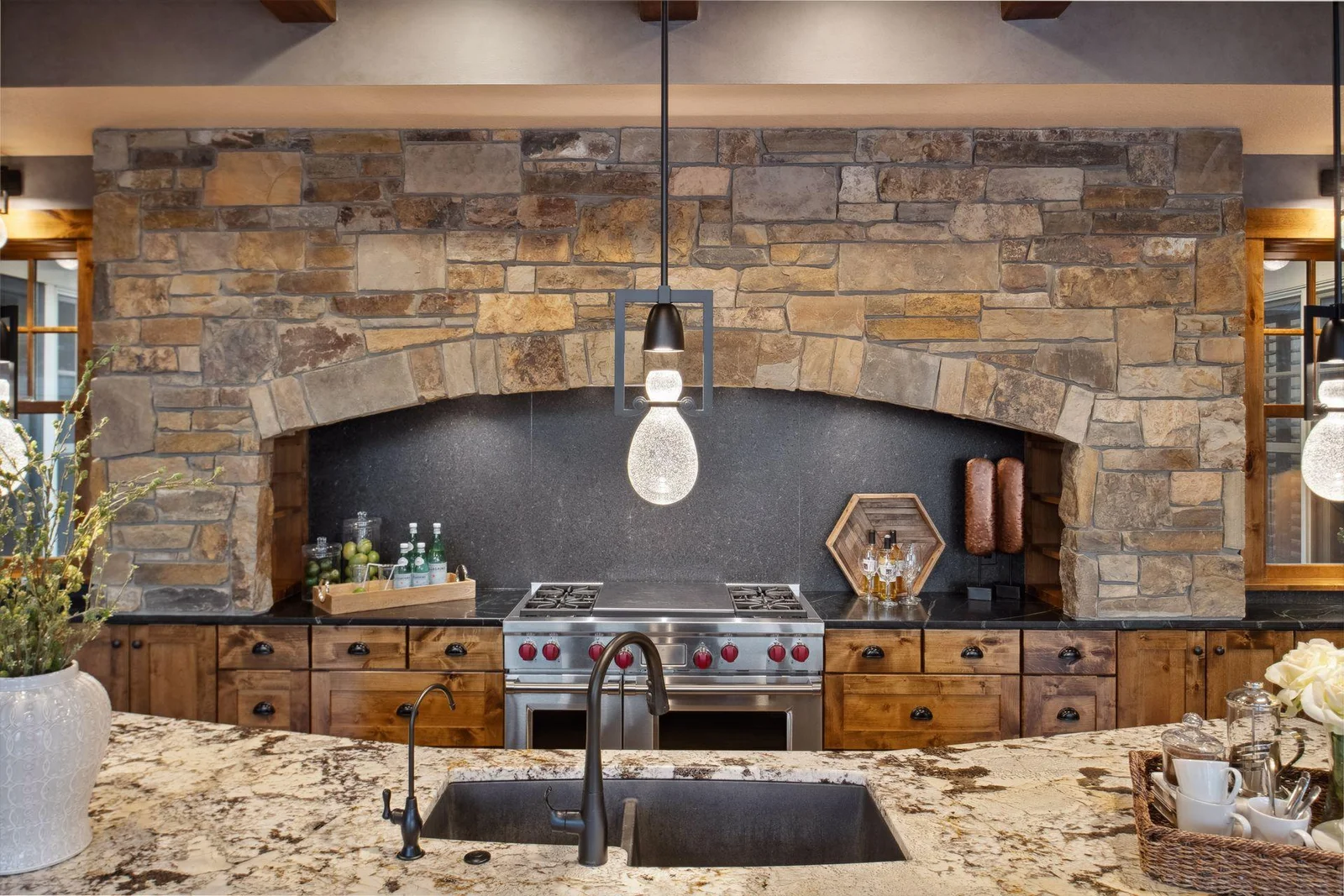 Featuring updated light fixtures, wood beams and soap stone perimeter counters. The 48” Wolf gas range with double ovens and range hood features a custom stone surround and honed granite backsplash