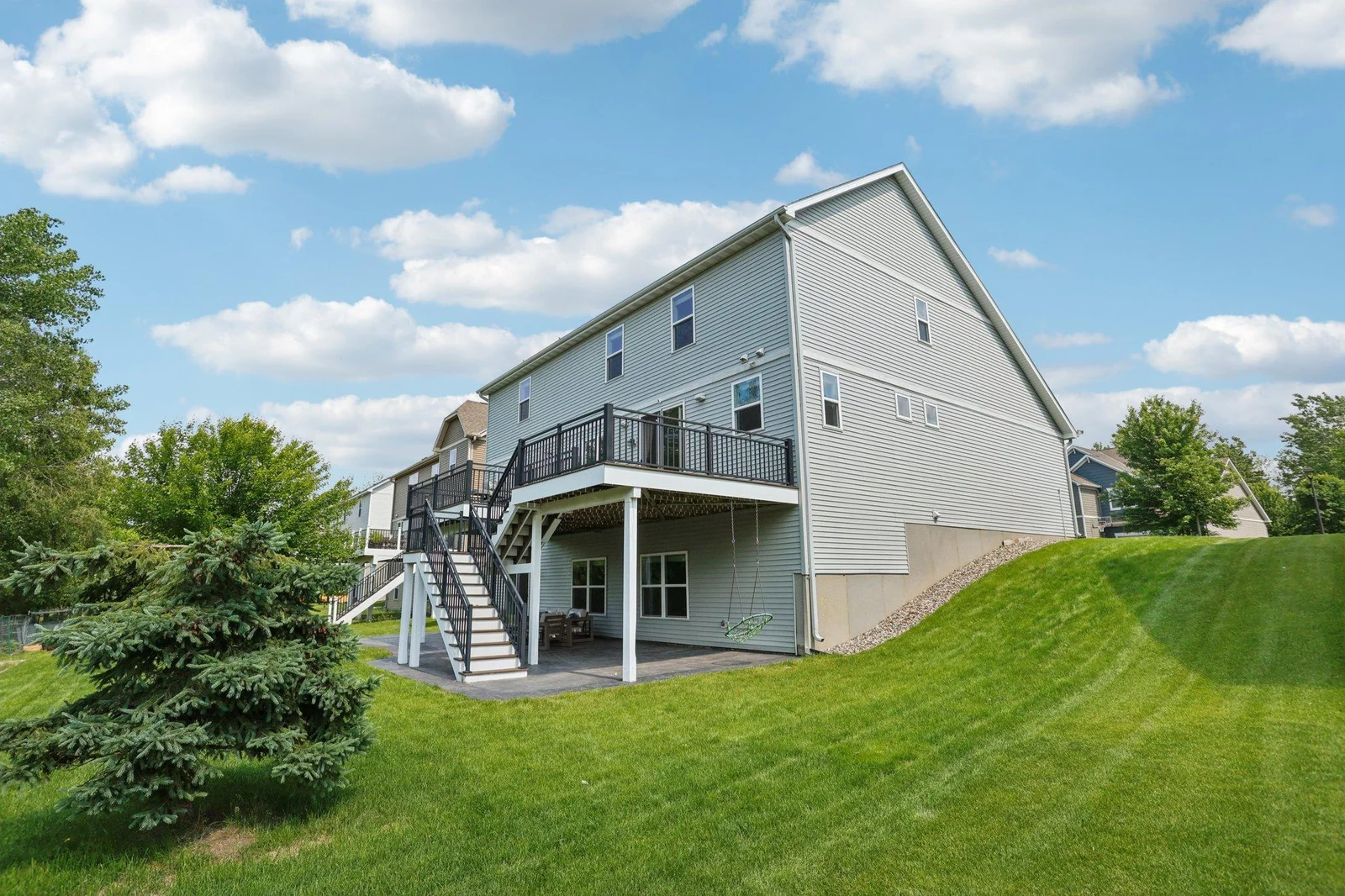 The staircase connects the deck to the lush, well-maintained lawn, creating a seamless indoor-outdoor living experience