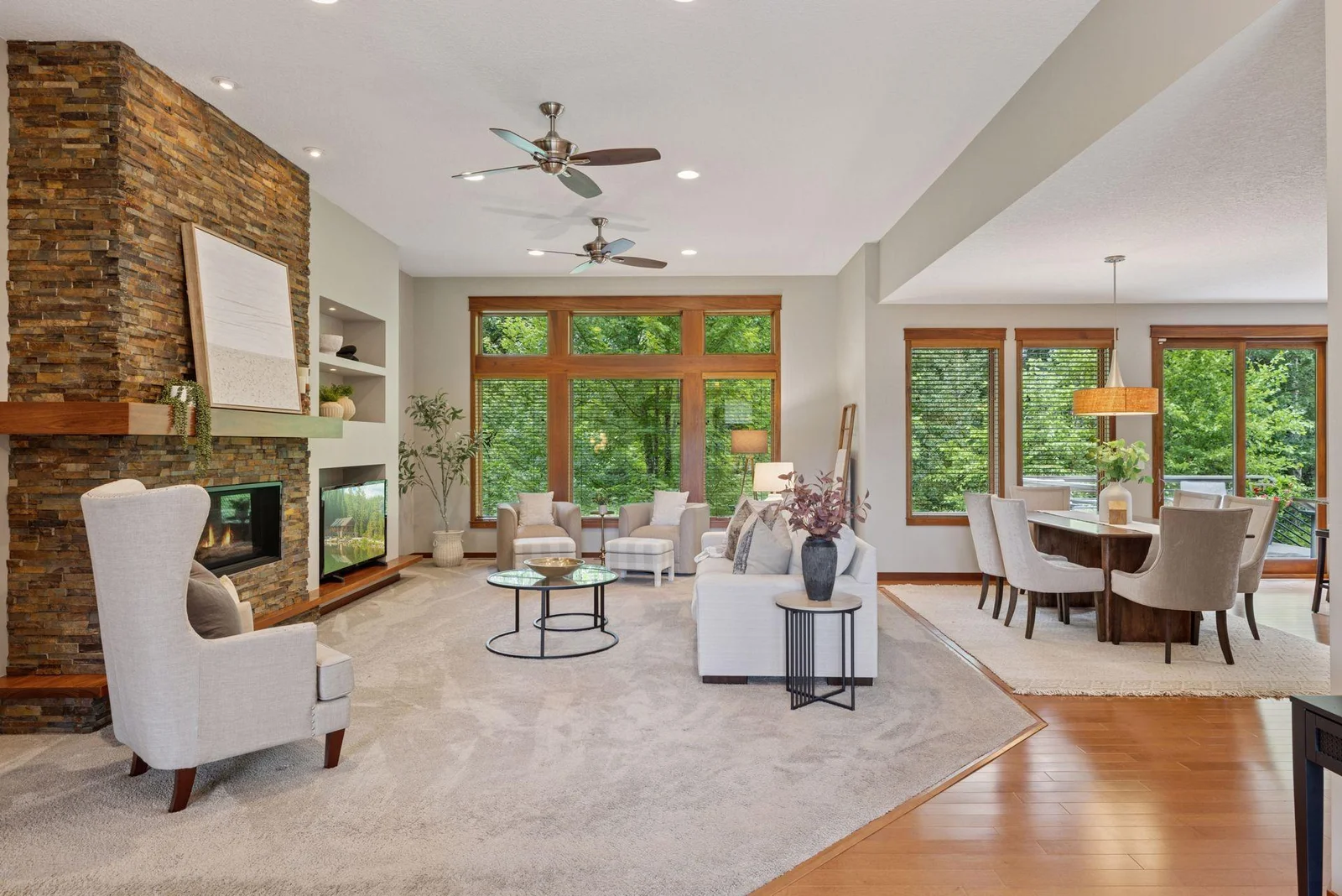From the foyer, the open-concept living room greets you with warmth, light, and big windows.
