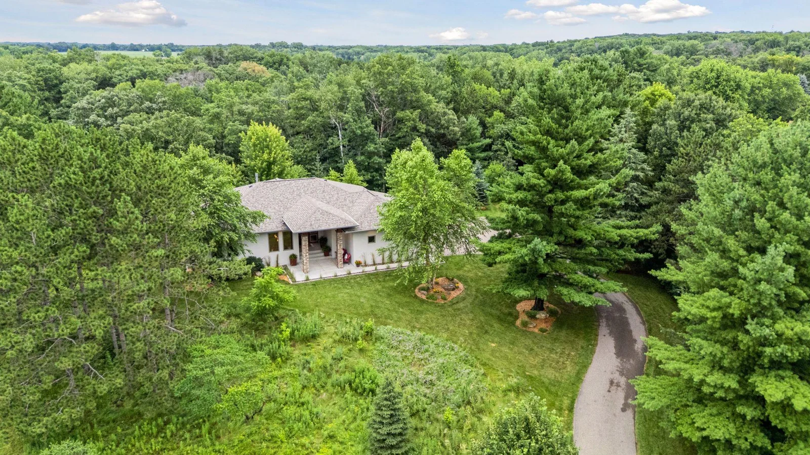 A peek at the showstopping grand entry—vaulted roofline, stone pillars, and a welcoming concrete patio.