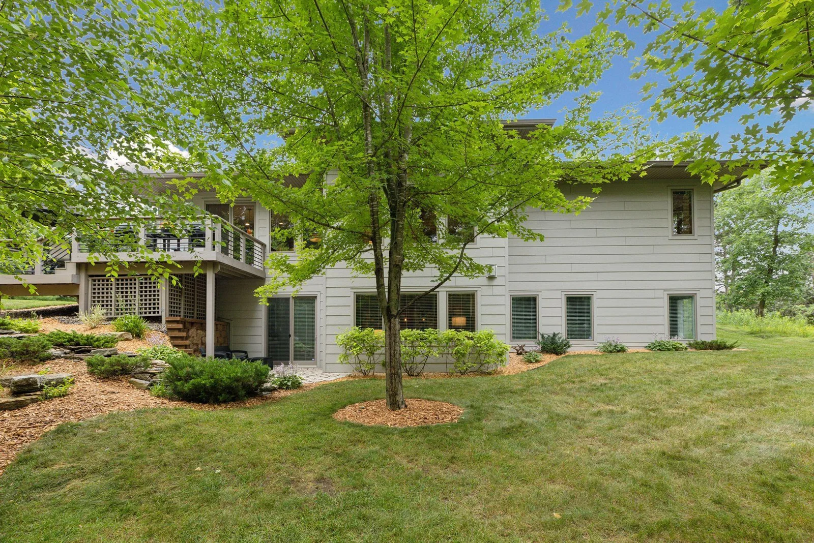 The backyard view of the home features modern railings, clean architecture, and multiple outdoor living spaces.