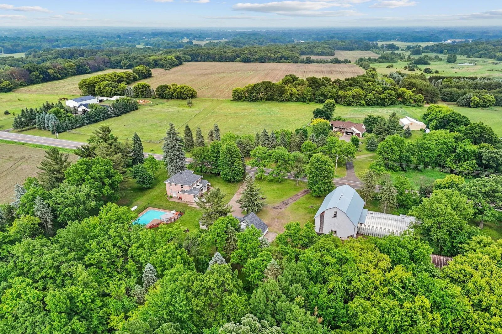 Aerial view of the farmhouse with pool nestled in the scenic countryside.