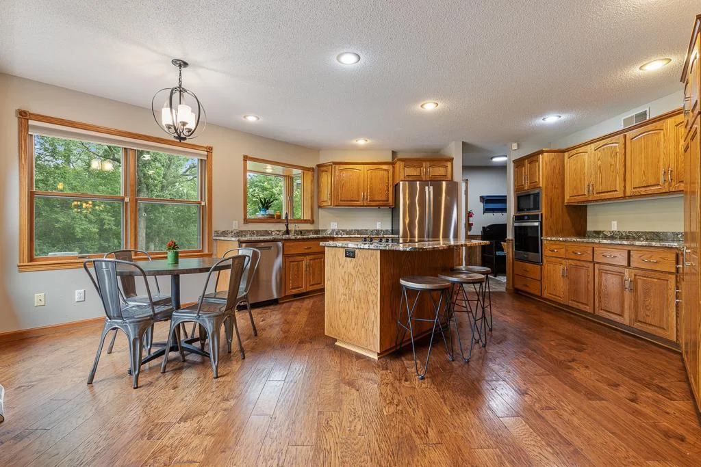 BEAUTIFUL custom kitchen features a center island, informal dining space, wall to wall windows, custom cabinetry, granite countertops, stainless steel appliances, and SO MUCH MORE!