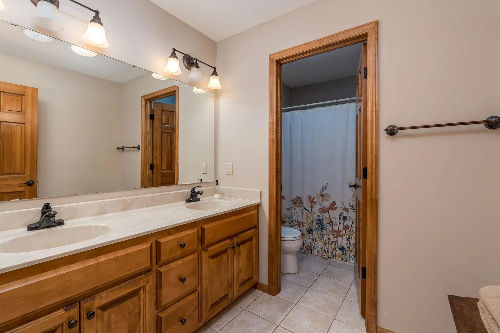 Hollywood style Full bathroom upstairs with double sinks and tiled floors.