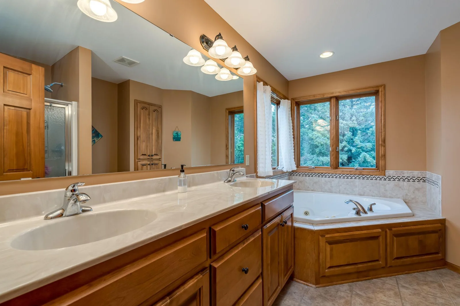 Spacious primary ensuite private bathroom with double sinks, large corner tub, separate shower & tiled floors.