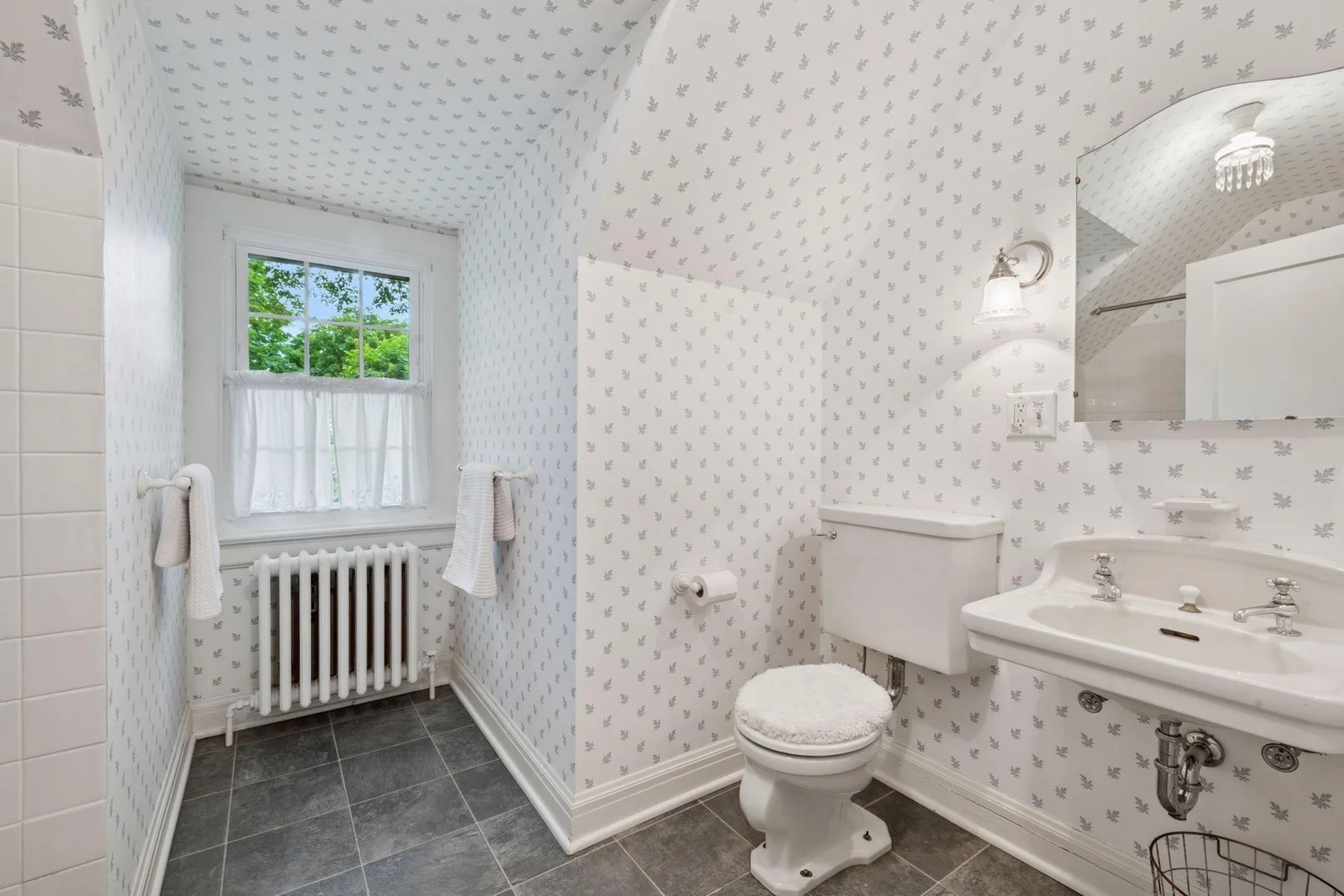The third-floor hall bath is oversized with vintage light fixtures and a charming archway.