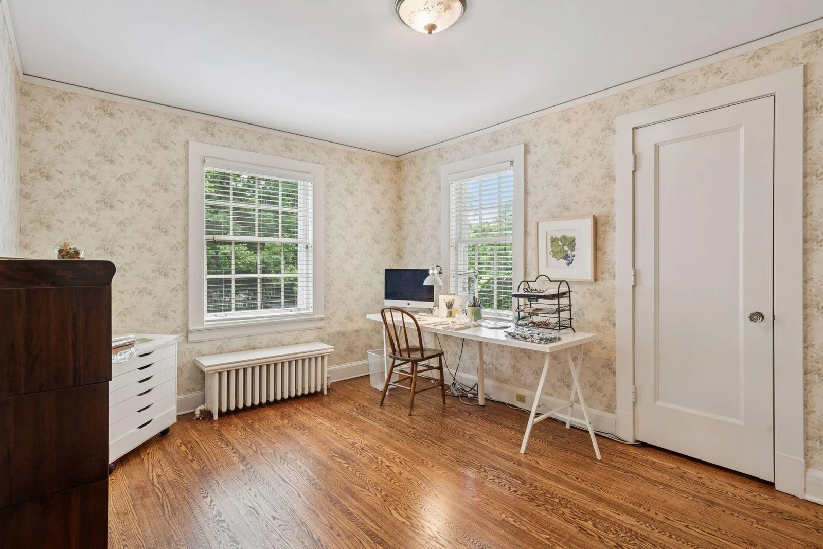 Timeless wallpaper in muted tones is the perfect backdrop in this bedroom, which is currently used as an artist's studio.