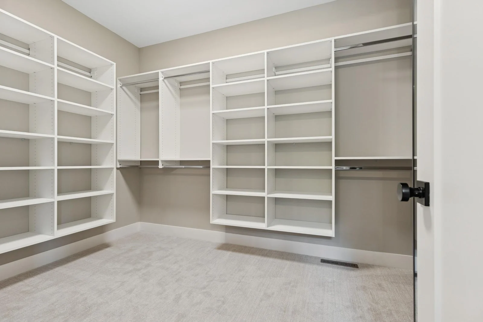 Large primary suite walk in closet with custom shelving.