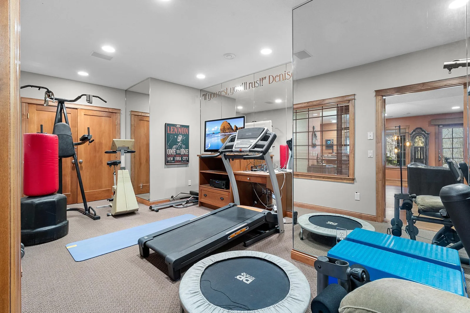Lower-level exercise room with space for several machines and weights. Mirrored walls and French, windowed doors to lower-level hallway. Ceiling speakers connect to media cabinet. Exercise equipment included.