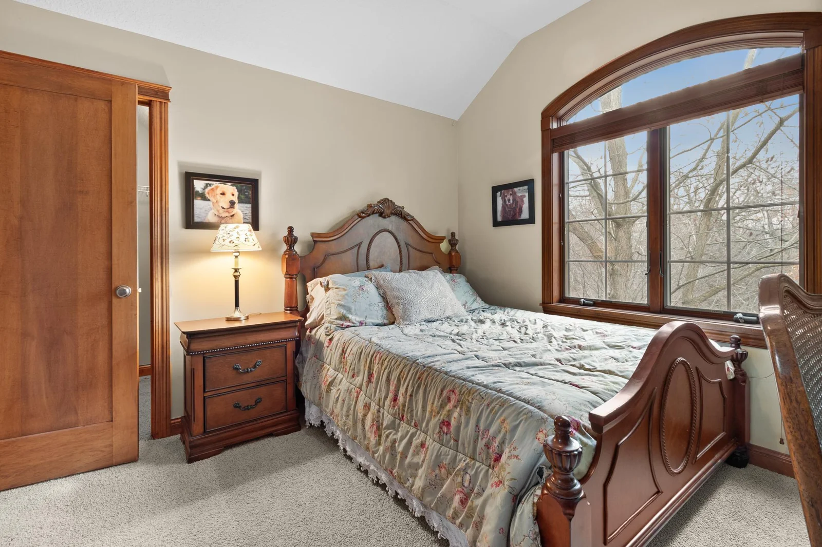 Upper-level second bedroom with view toward large windows and walk-in closet.