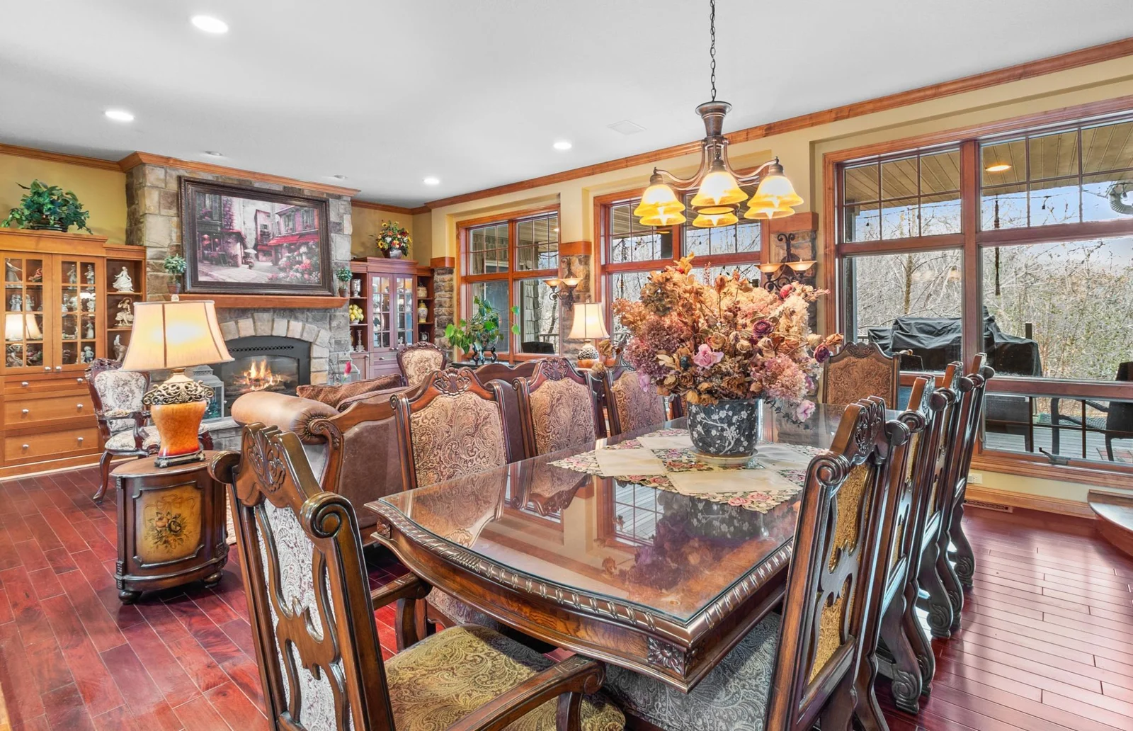 Formal Dining Room with mahogany hardwood floors, shown with connecting living room and fireplace, stone accented wall with wall sconces