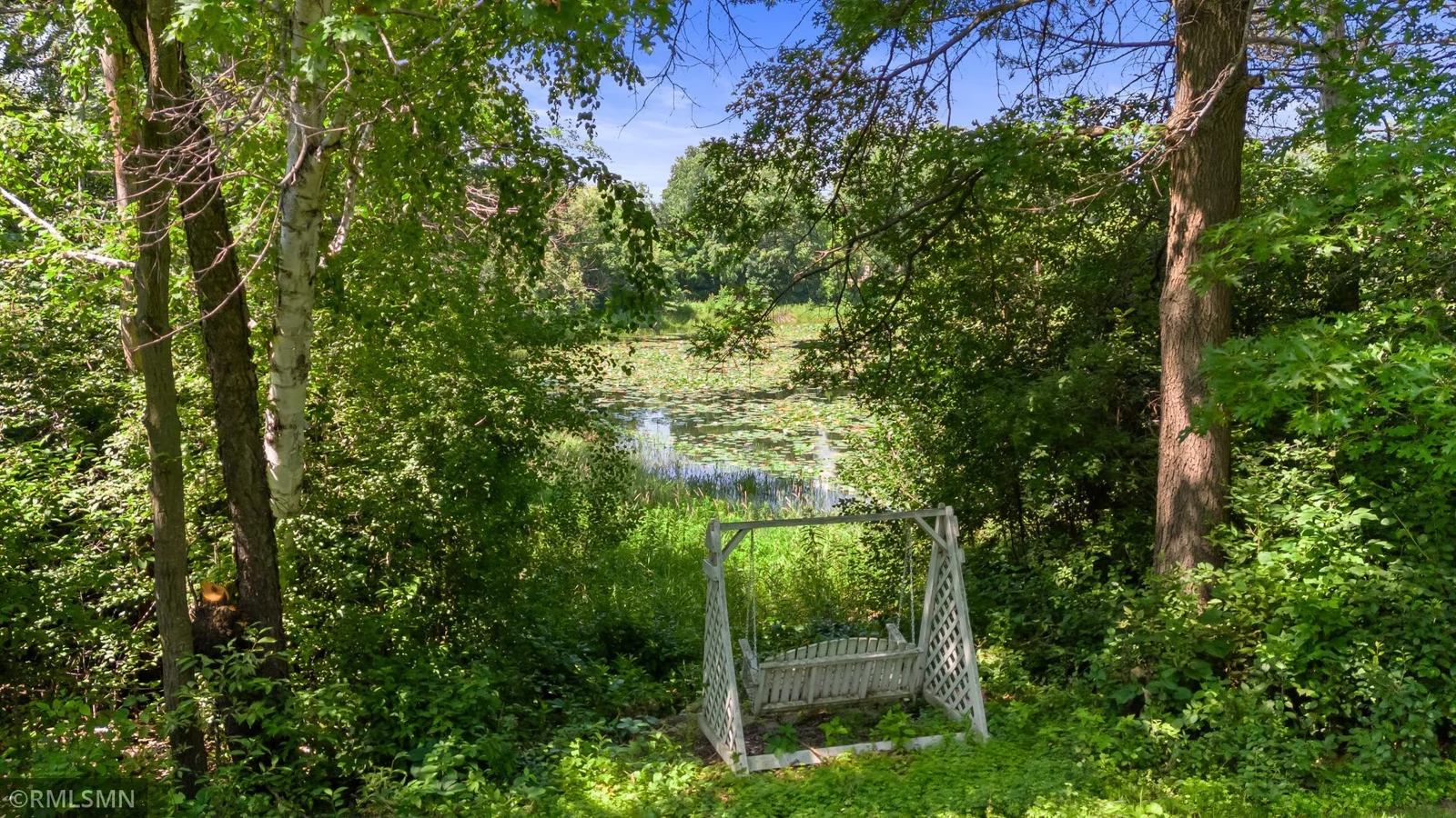 From yard toward pond at the height of summer. Relax on swing or launch your paddle boat or kayak.