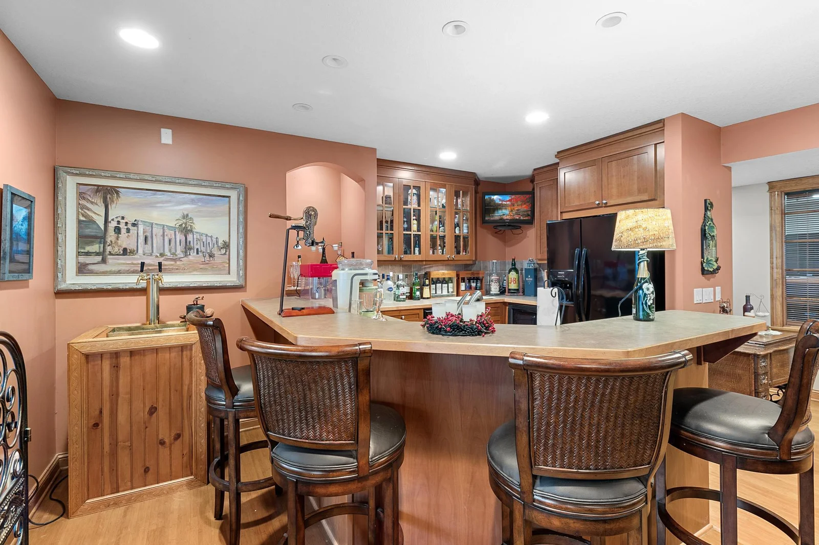 Lower-level recreation room wet bar. Cherry cabinets, sink, garbage disposal, dishwasher, full-sized refrigerator, separate wine refrigerator, microwave, TV included in listing