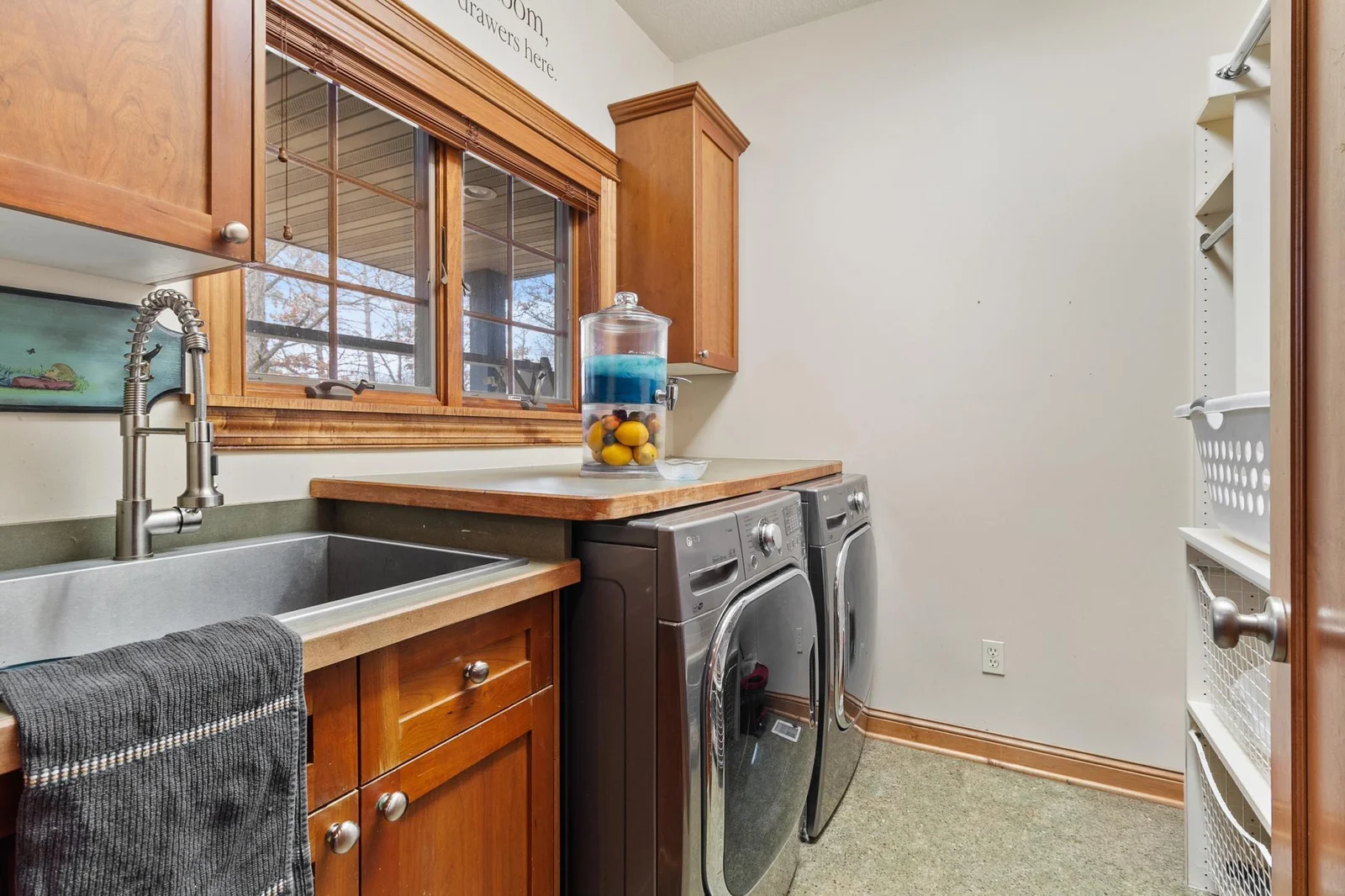 Laundry with included recent LG washer and natural gas LG dryer. Deep laundry tub, clothes sorting counter and storage shelves.