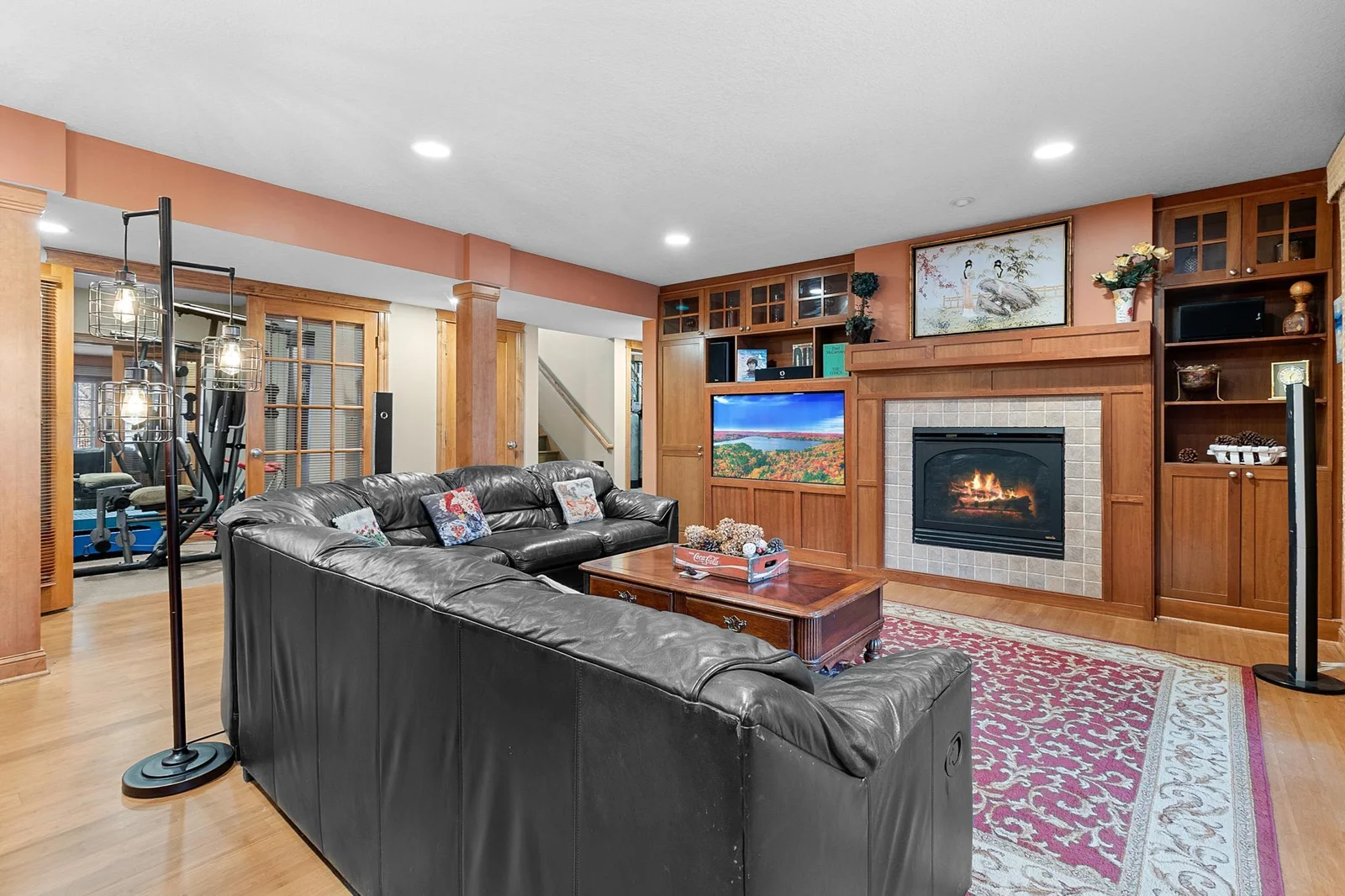 Lower-level recreation room with fireplace, cherry media cabinets. Ceiling speakers connect to media cabinet.