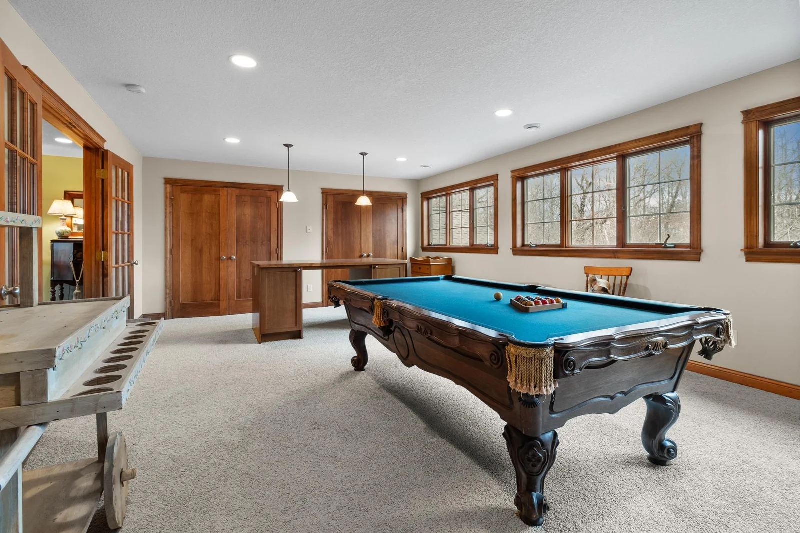 Upper-level billiard / craft room showing French doors, storage closets. Pool table included. Windows overlooking back yard, woods and private horse paddock.
