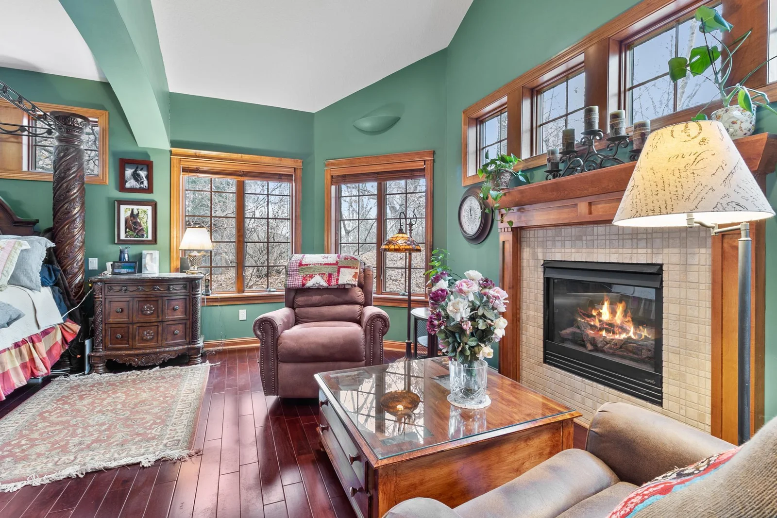 Primary bedroom sitting area with view towards woods, fireplace, extra high ceilings, mahogany hardwood floors.