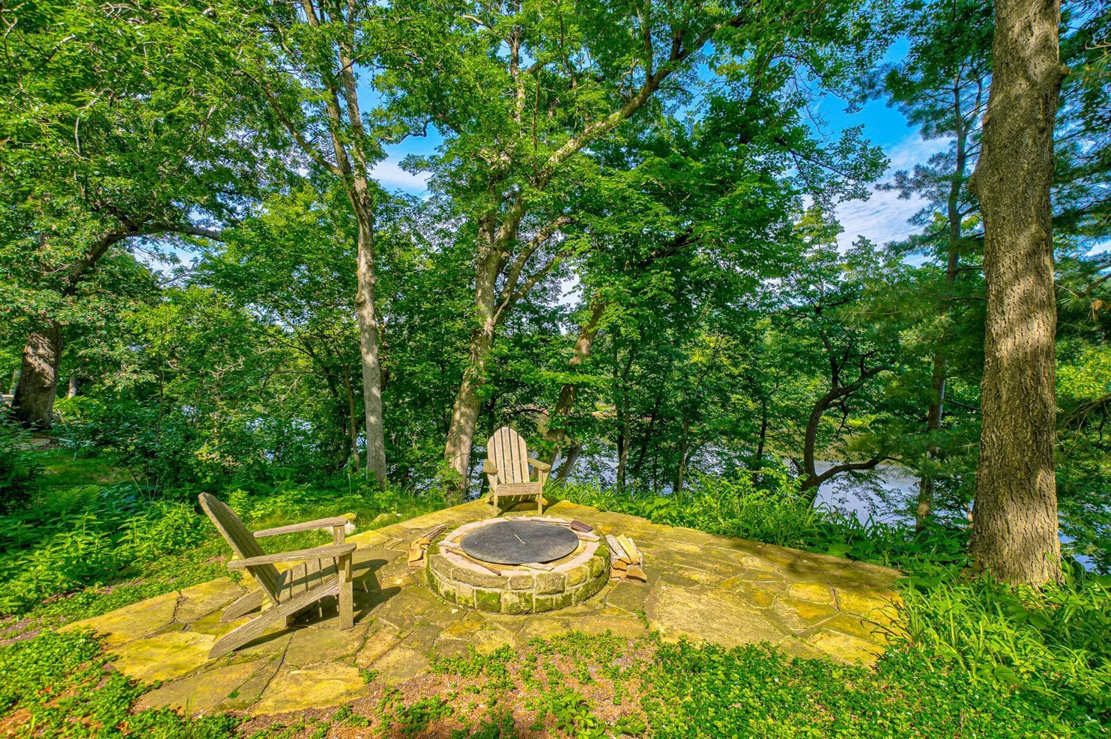 This north patio area off the screen porch deck has a built-in fire pit and a beautiful view of the river.