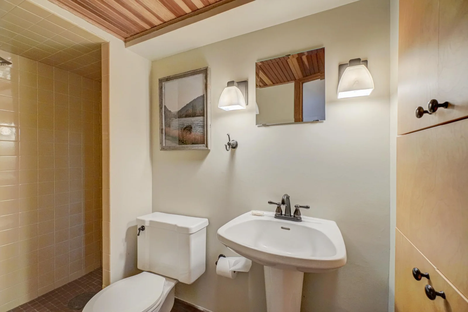 The lower level bathroom has a tiled walk-in shower and custom built-in storage.