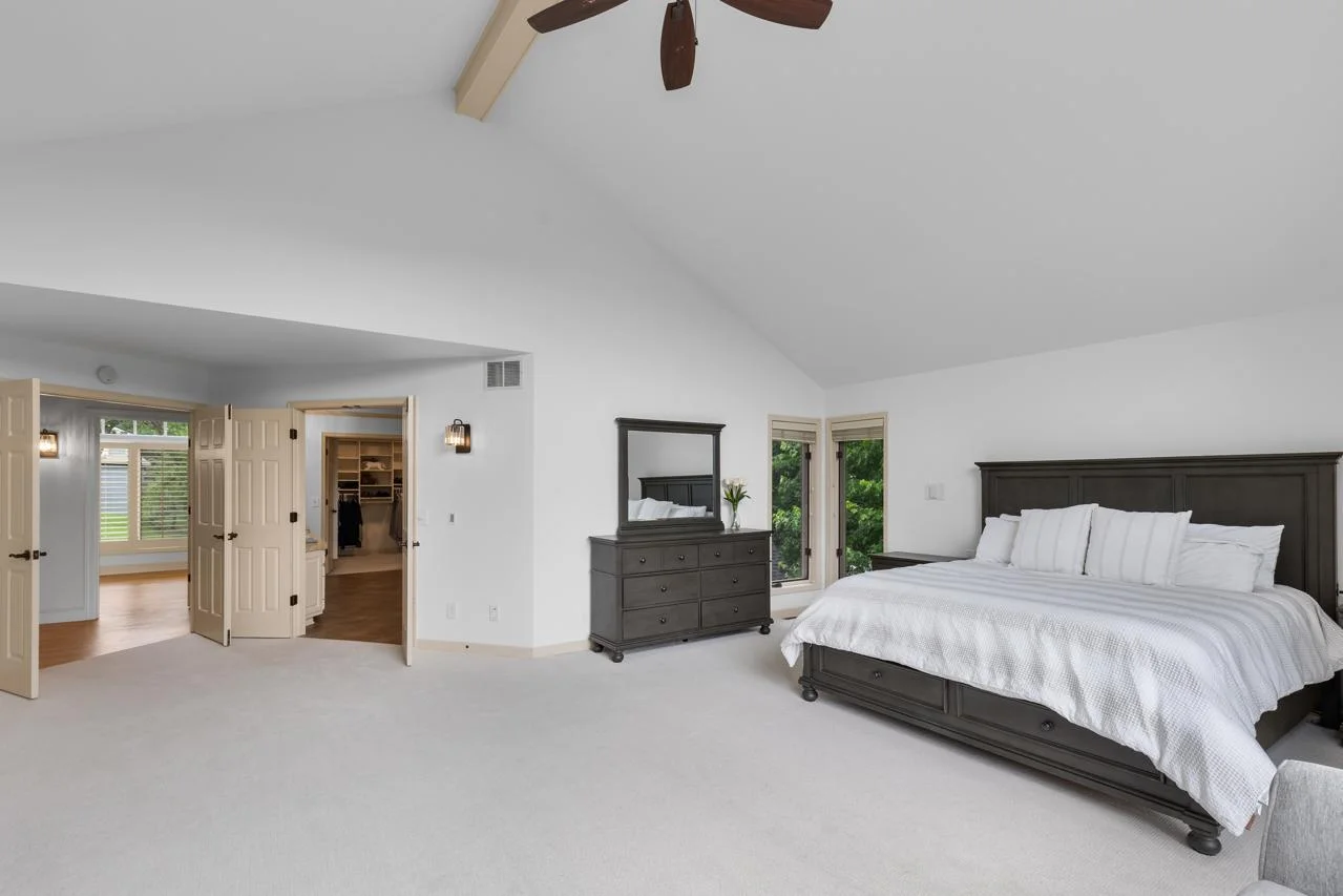 The expansive primary bedroom is a true sanctuary, featuring soaring vaulted ceilings, a cozy fireplace, and dramatic floor-to-ceiling windows that flood the space with natural light.