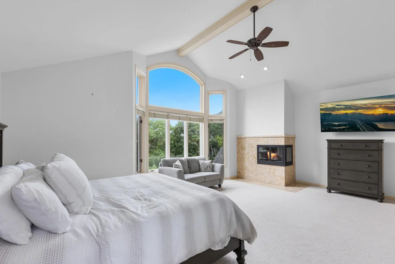 The expansive primary bedroom is a true sanctuary, featuring soaring vaulted ceilings, a cozy fireplace, and dramatic floor-to-ceiling windows that flood the space with natural light.