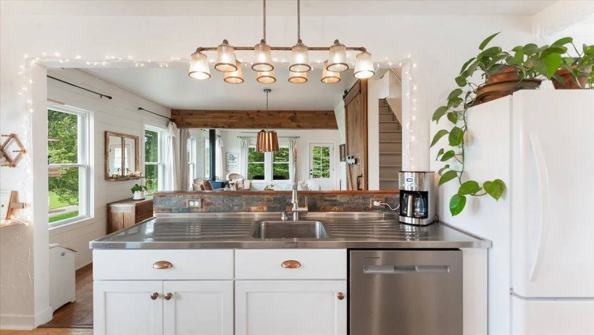 Kitchen features a stainless steel sink and a view into the living room/ dining room.