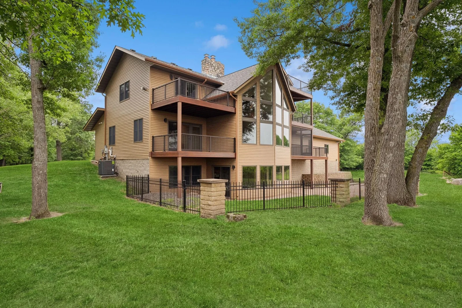 Rear view of home which features multiple decks and fenced patio