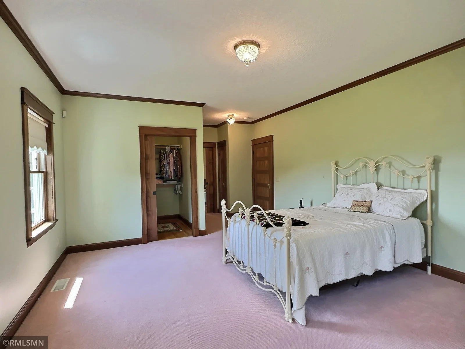 This serene primary suite is a spacious and elegant retreat, filled with natural light, rich wood accents and vintage-inspired charm.
