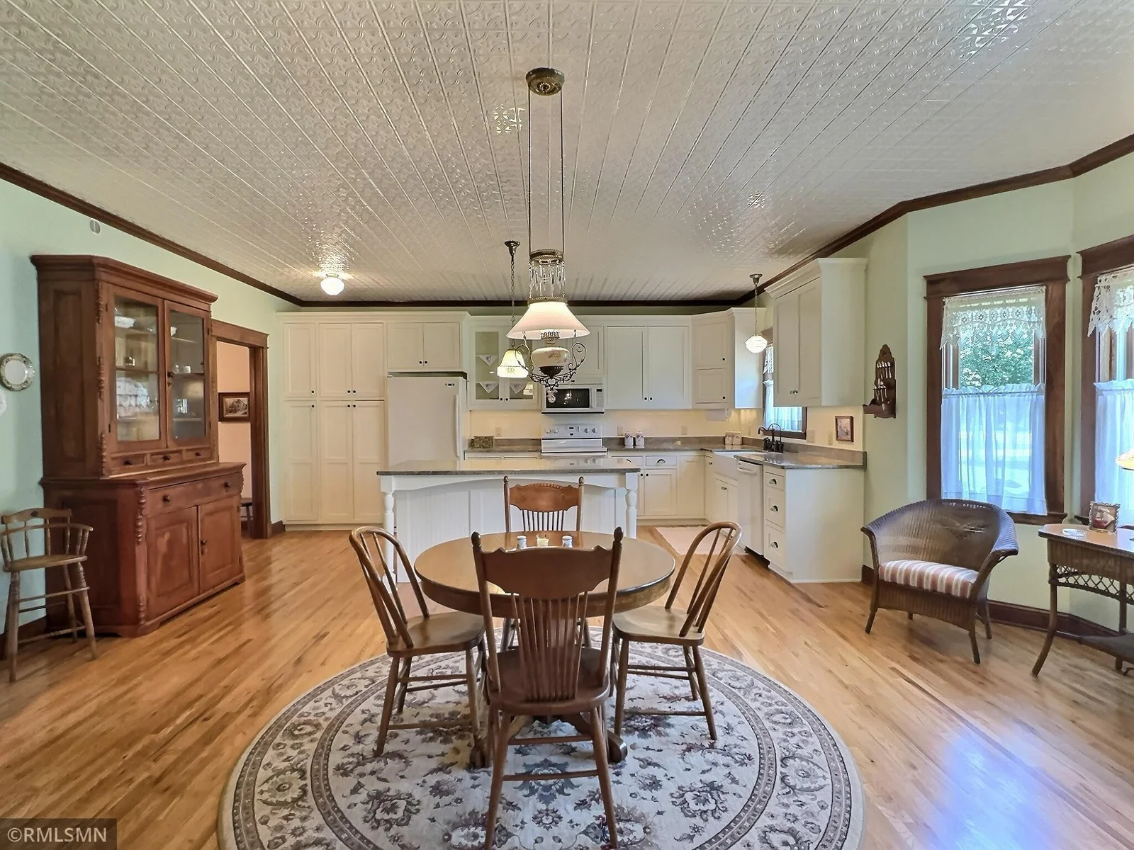 Seamlessly connected to the kitchen, the space features classic crown molding, warm hardwood floors, and a vintage-inspired tin ceiling.