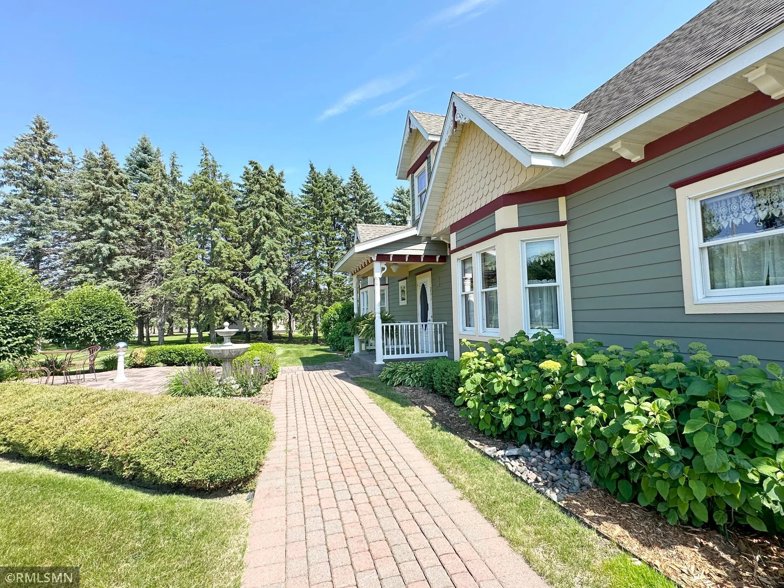 This picturesque front entry welcomes you with classic charm and meticulous landscaping. A brick paver walkway leads to a covered porch.