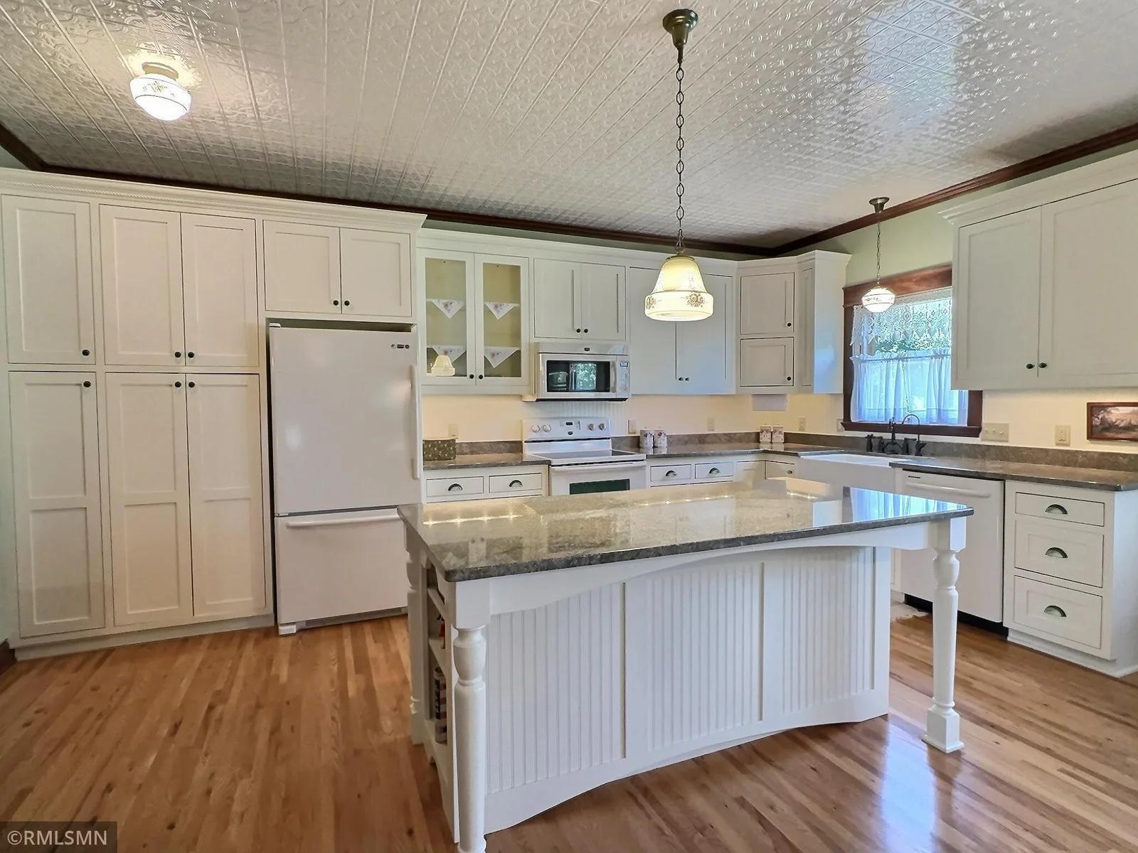 This beautifully designed kitchen blends vintage charm with everyday functionality with custom white cabinetry finished with glass accents.