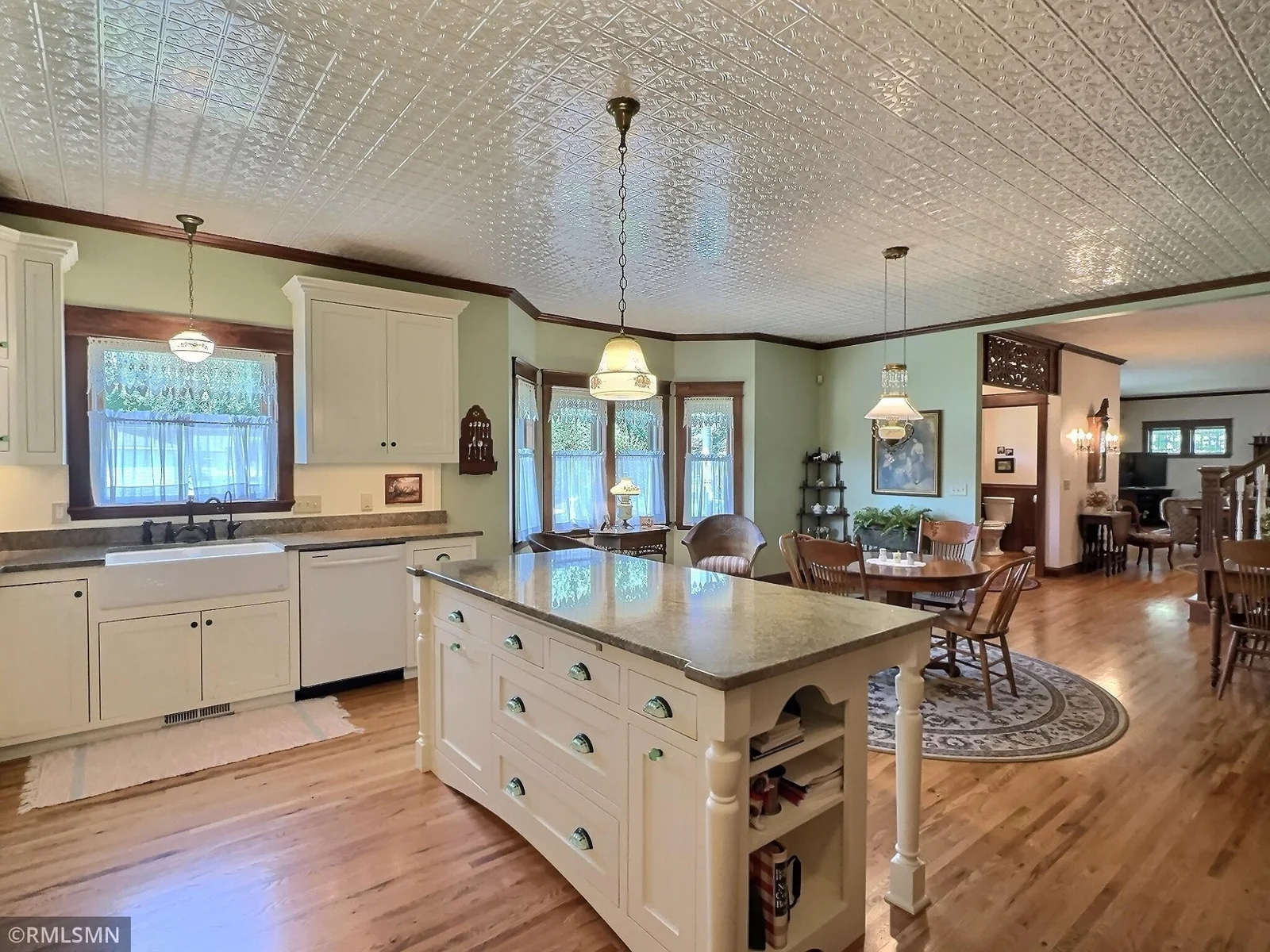 A decorative tin-style ceiling and classic pendant lighting add timeless character, while warm wood floors tie the heart of the home together.