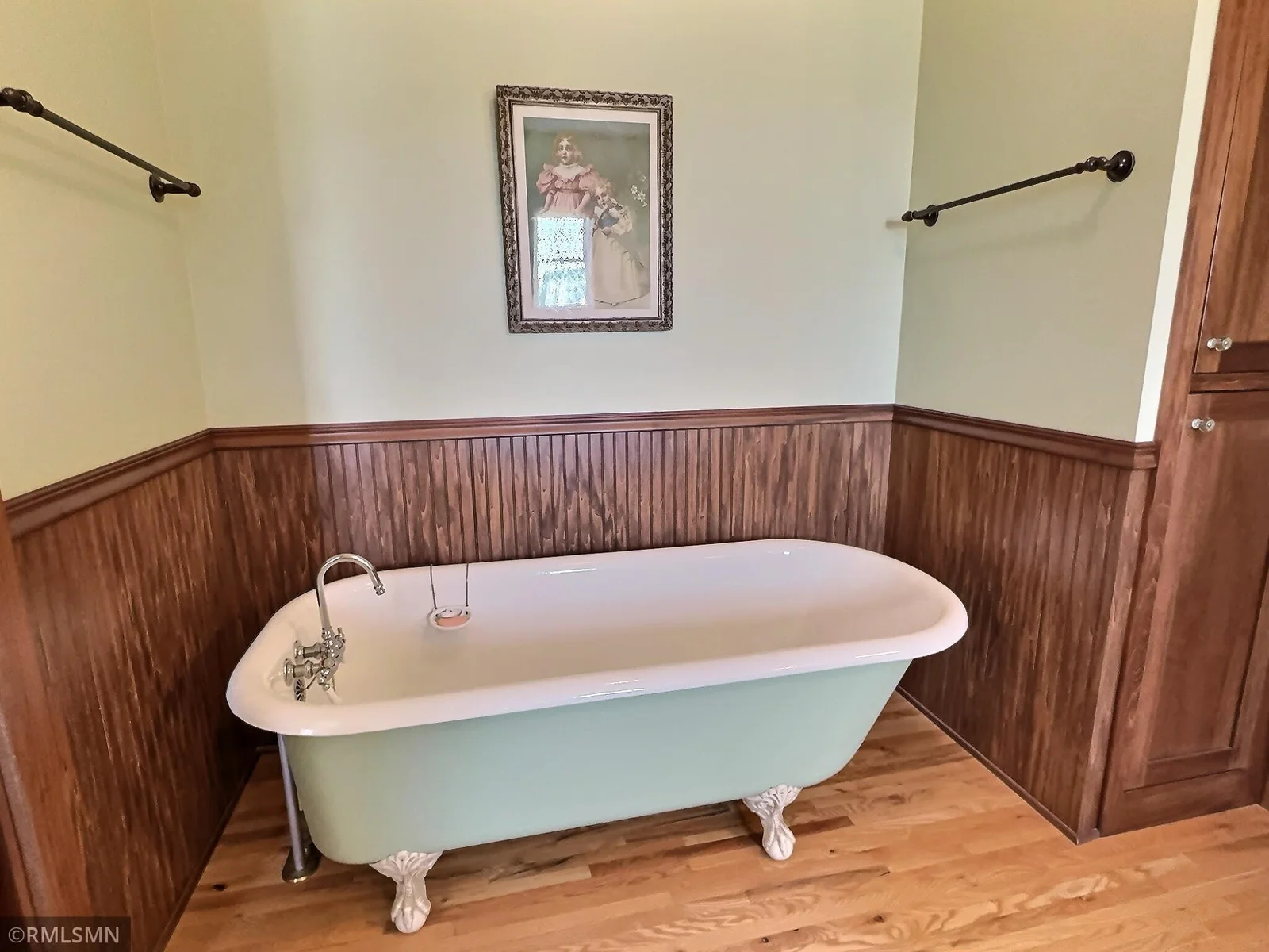 A classic clawfoot tub takes center stage, offering a perfect spot to unwind...rich wood cabinetry and wainscoting add warmth.
