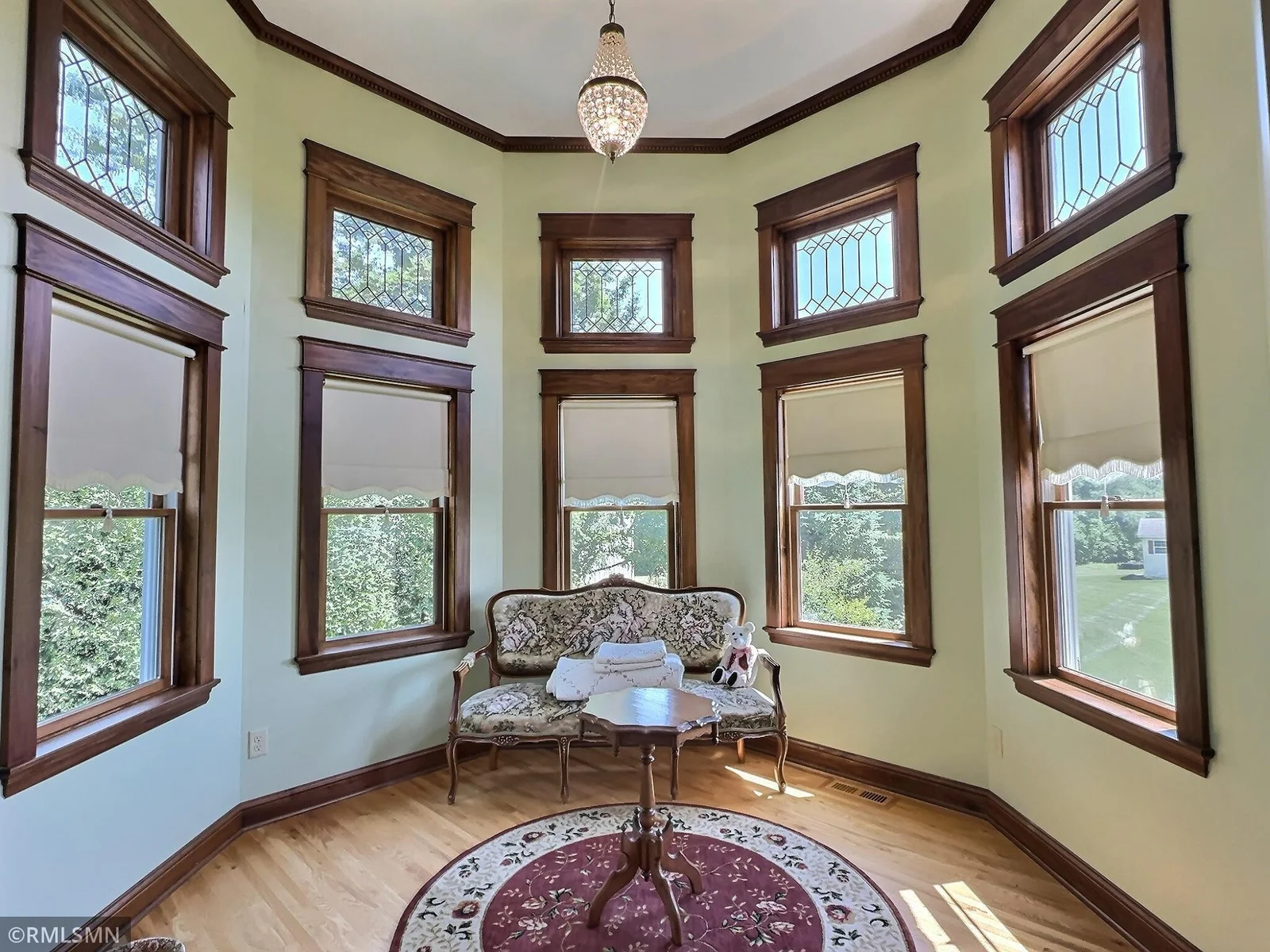 Tucked within the turret of the home, this breathtaking sunroom is a true sanctuary surrounded by tall windows with elegant leaded glass accents.