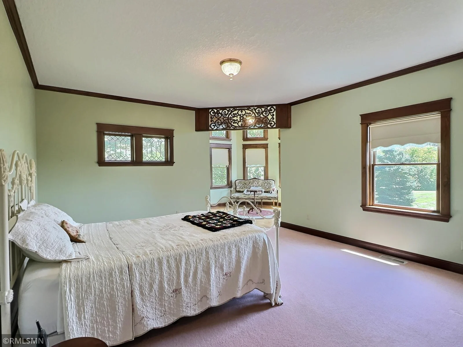 Featuring soft hues, rich wood trim, and a cozy sun room framed by an ornate wood transom, the space feels both grand and welcoming.