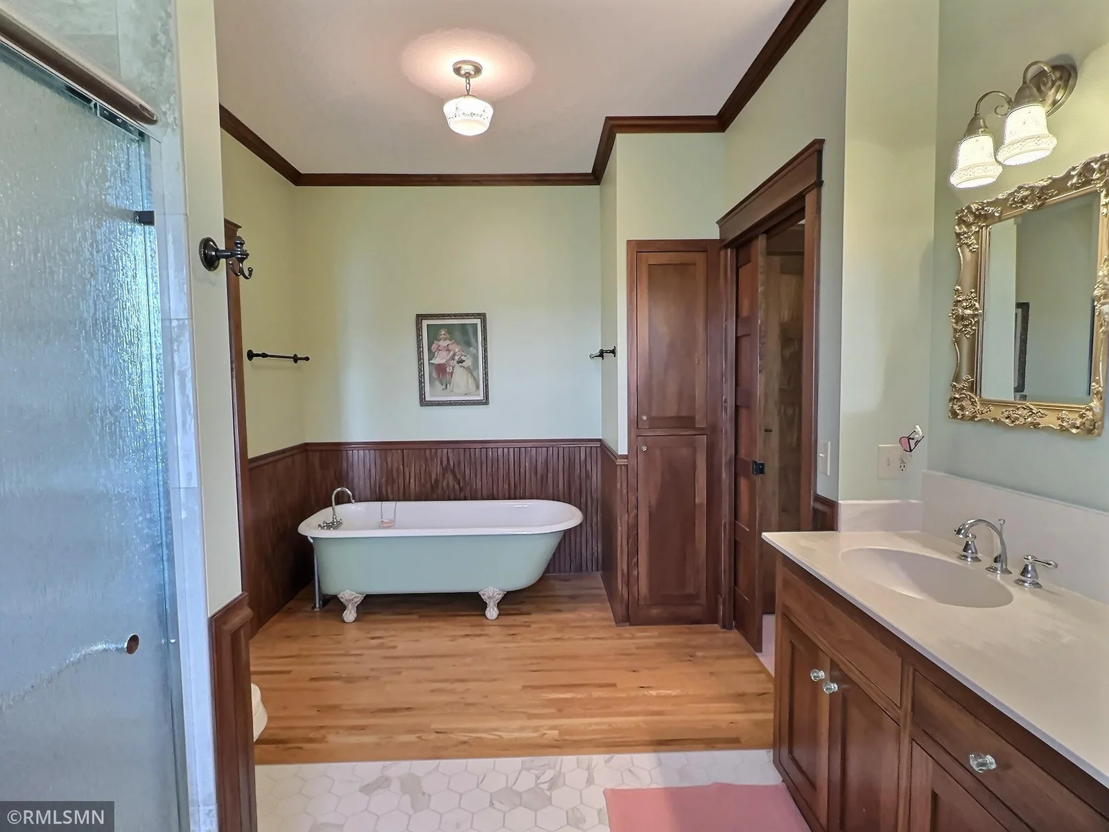 This beautifully appointed bathroom blends vintage elegance with modern convenience with large counter and shower with tile surround.