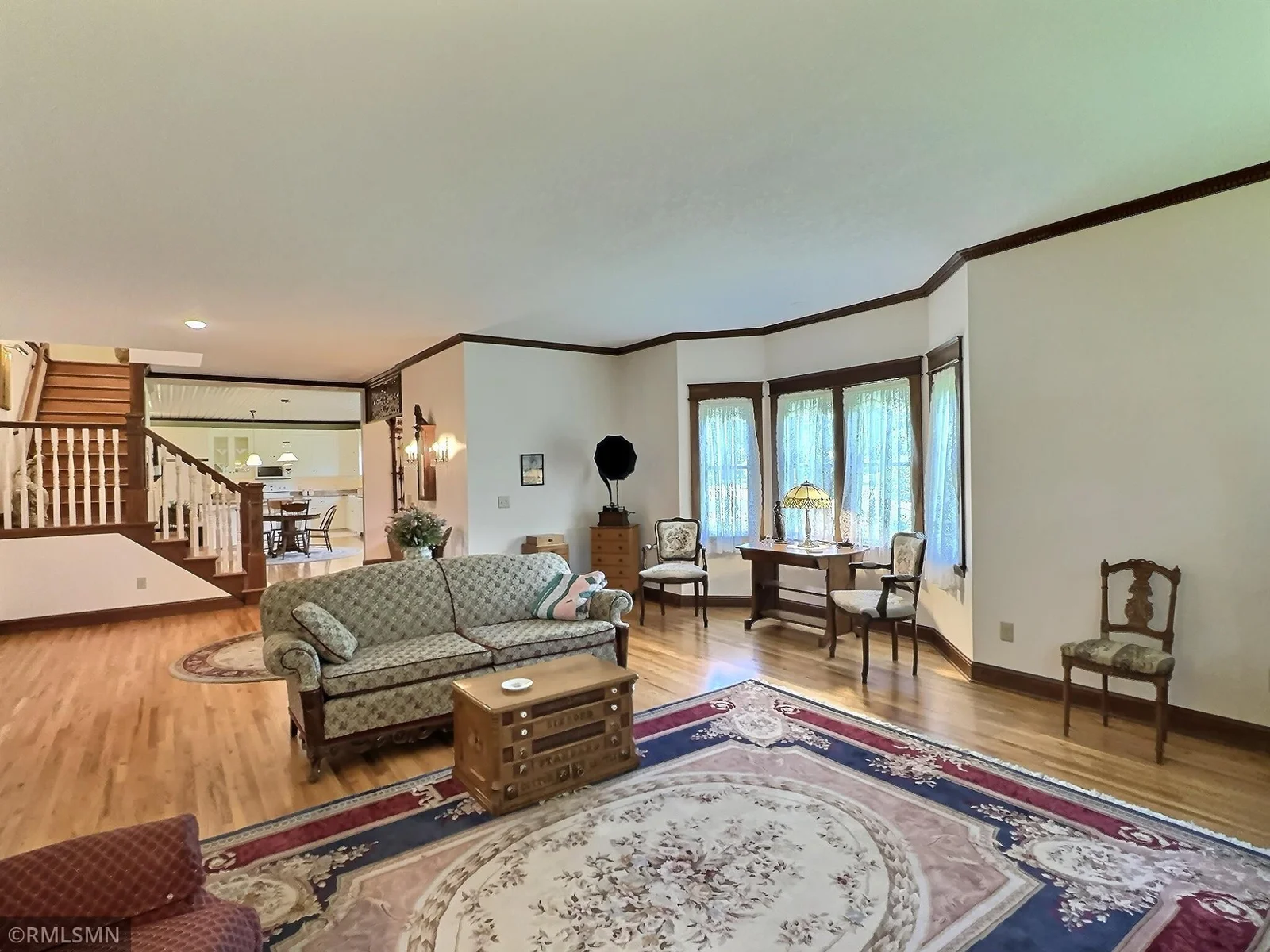 This gracious living room exudes warmth and timeless elegance with its hardwood floors, crown molding, and inviting bay window.