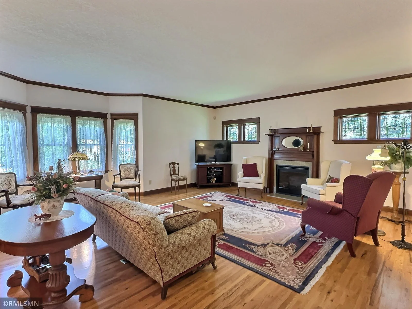 The living room offers a cozy yet sophisticated atmosphere, anchored by a stunning fireplace flanked by gorgeous stained glass windows.