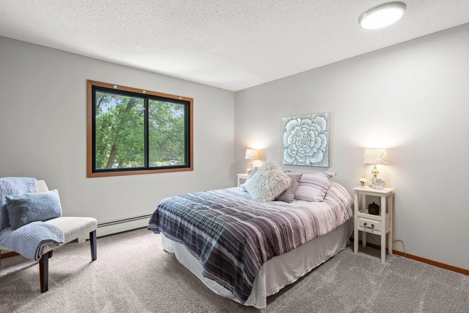 New carpet plus neutral decor carry into the spacious bedroom featuring a large window for ample light.