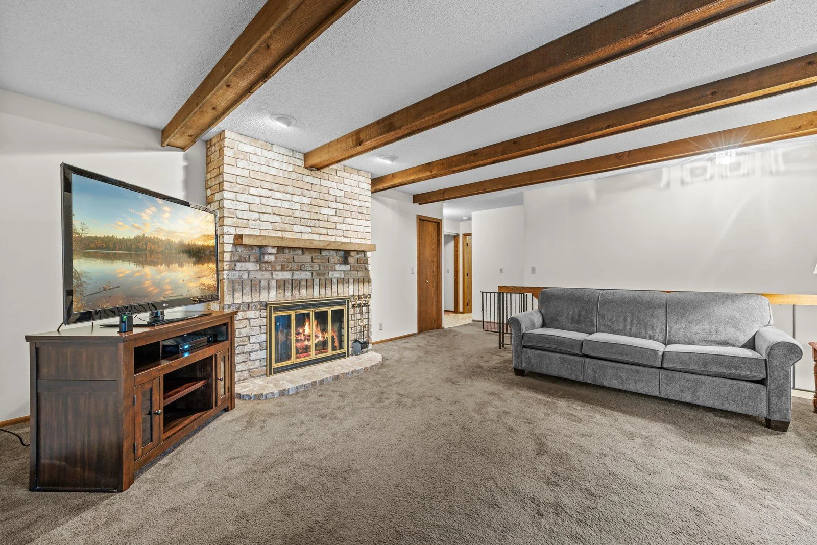 The living room is super spacious and features a brick fireplace and wonderful exposed beams.