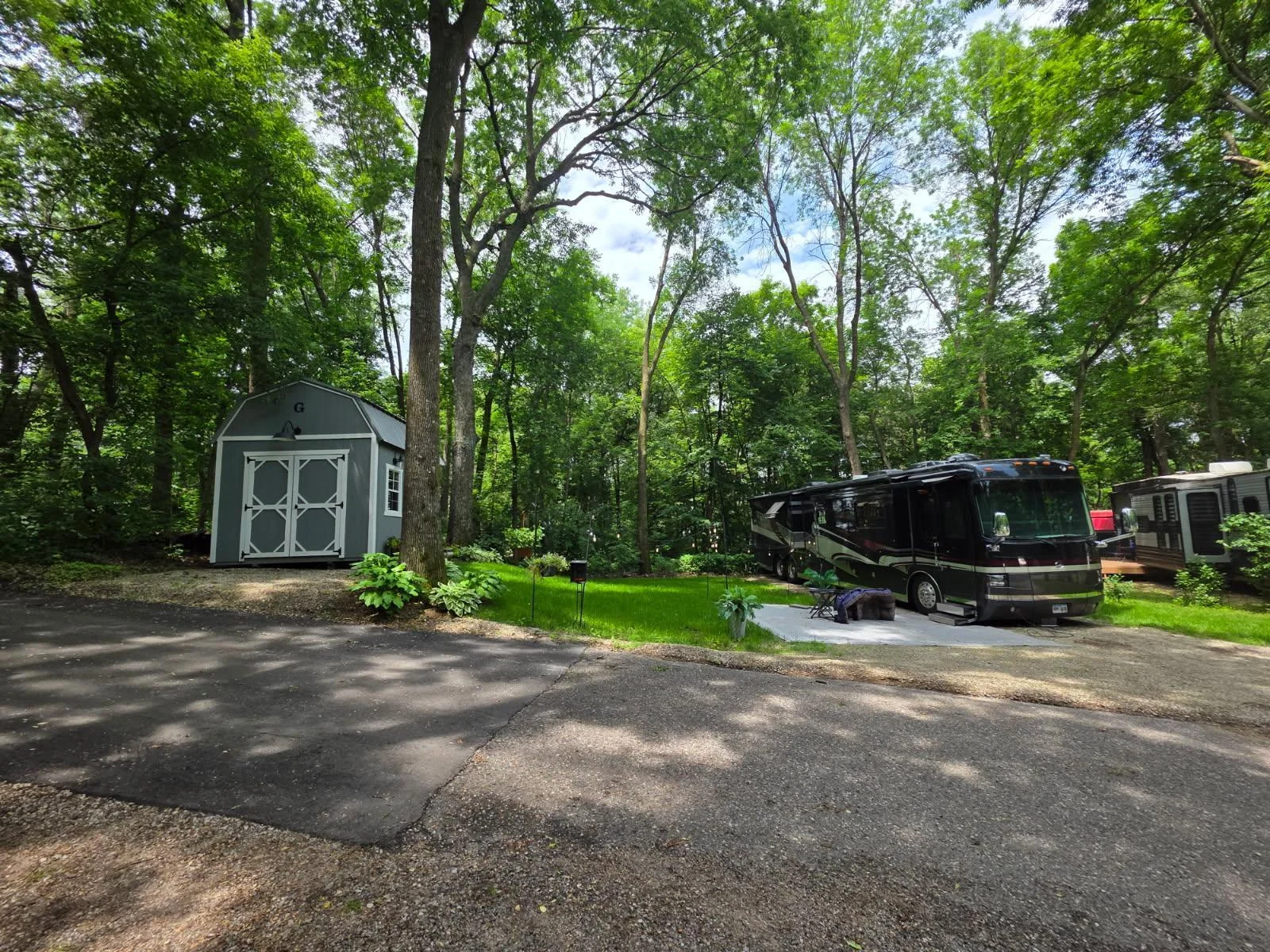 Unit 63 has pretty trees, green grass, a great parking pad for a heavy RV and a nice level pad for a shed.