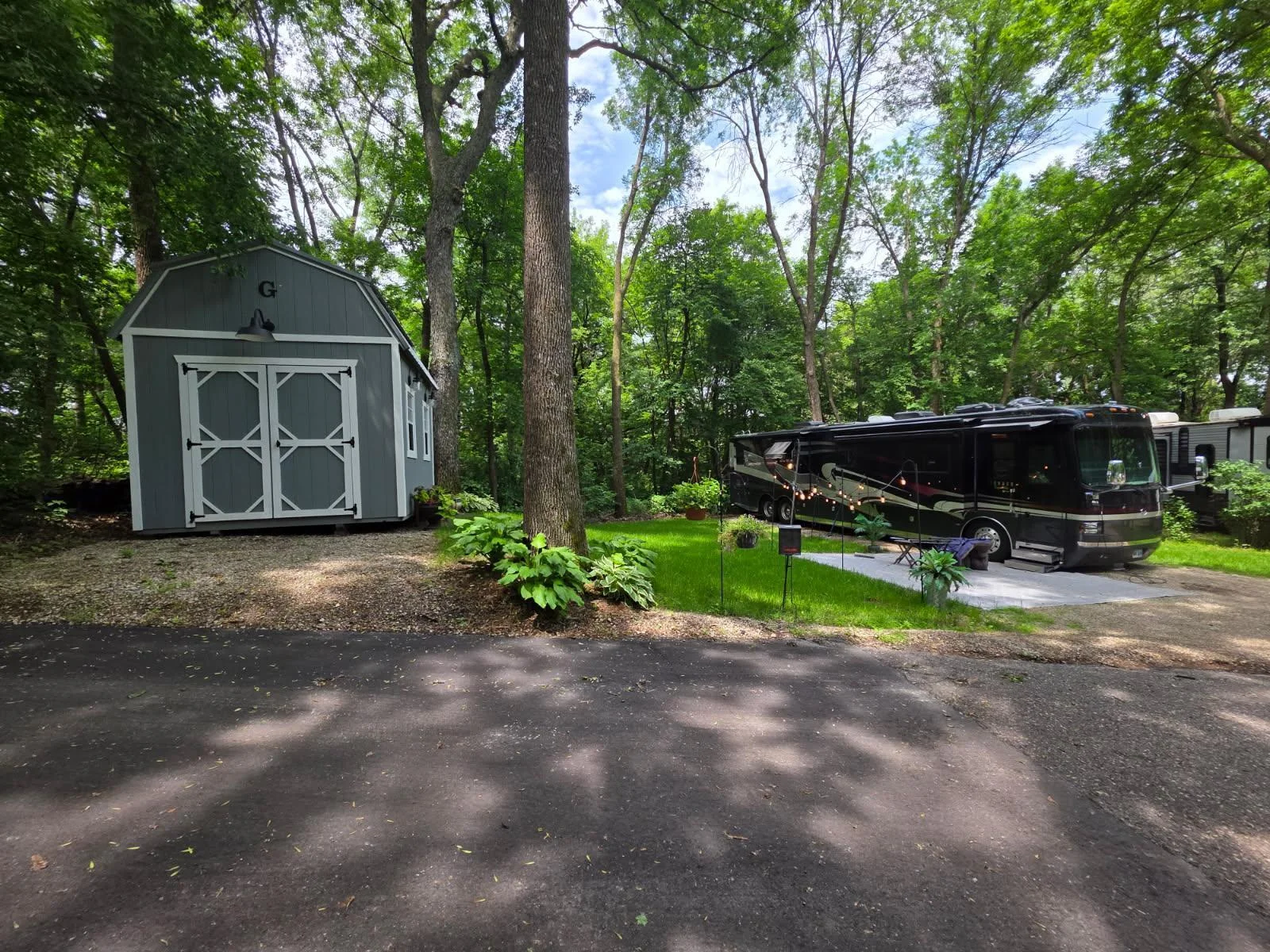 Unit 63 has pretty trees, green grass, a great parking pad for a heavy RV and a nice level pad for a shed.