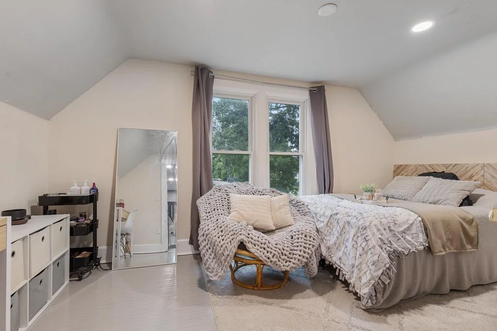 This roomy upstairs bedroom shines with fresh paint and modern recessed lighting, creating a bright and inviting space.