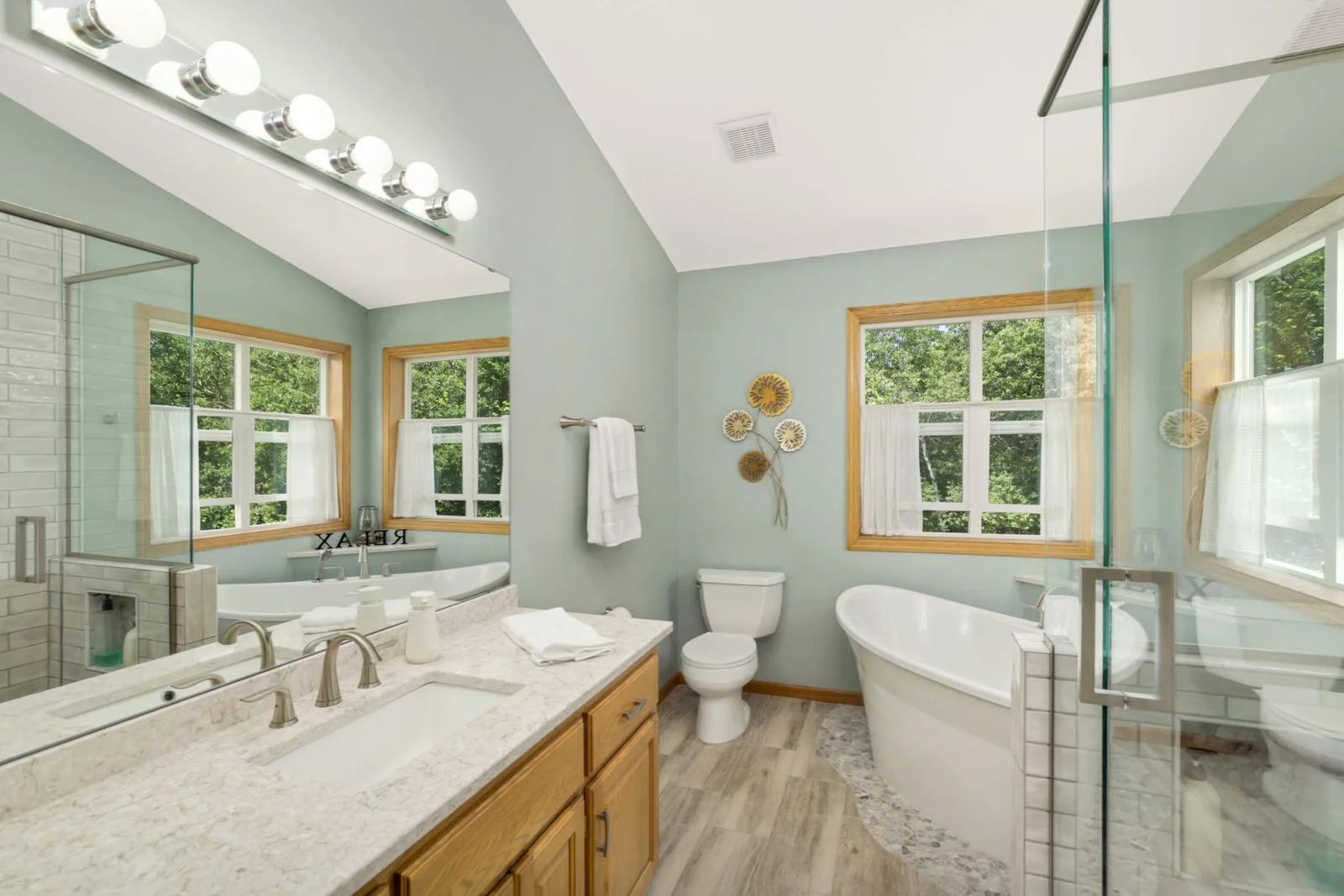 Updated owner’s bathroom features a luxurious soaking tub and a sleek frameless glass shower for a spa-like experience.