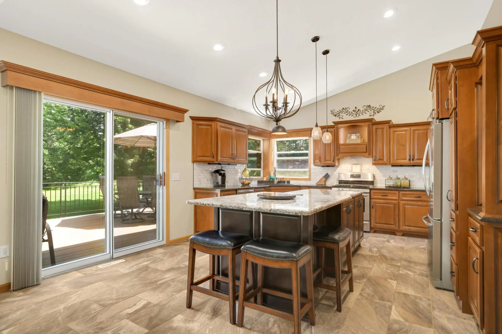 Spacious modern kitchen features an oversized granite island, heated tile floors, and an abundance of cabinetry and prep space—perfect for cooking and entertaining