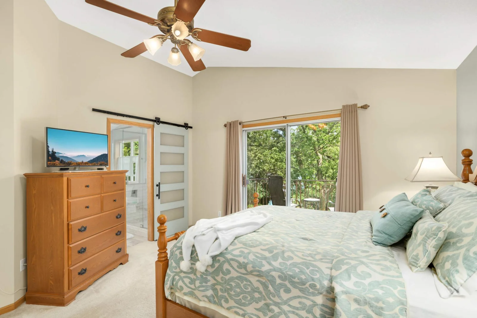 The vaulted owner’s suite offers a spacious walk-in closet and a charming Juliet balcony with serene views.